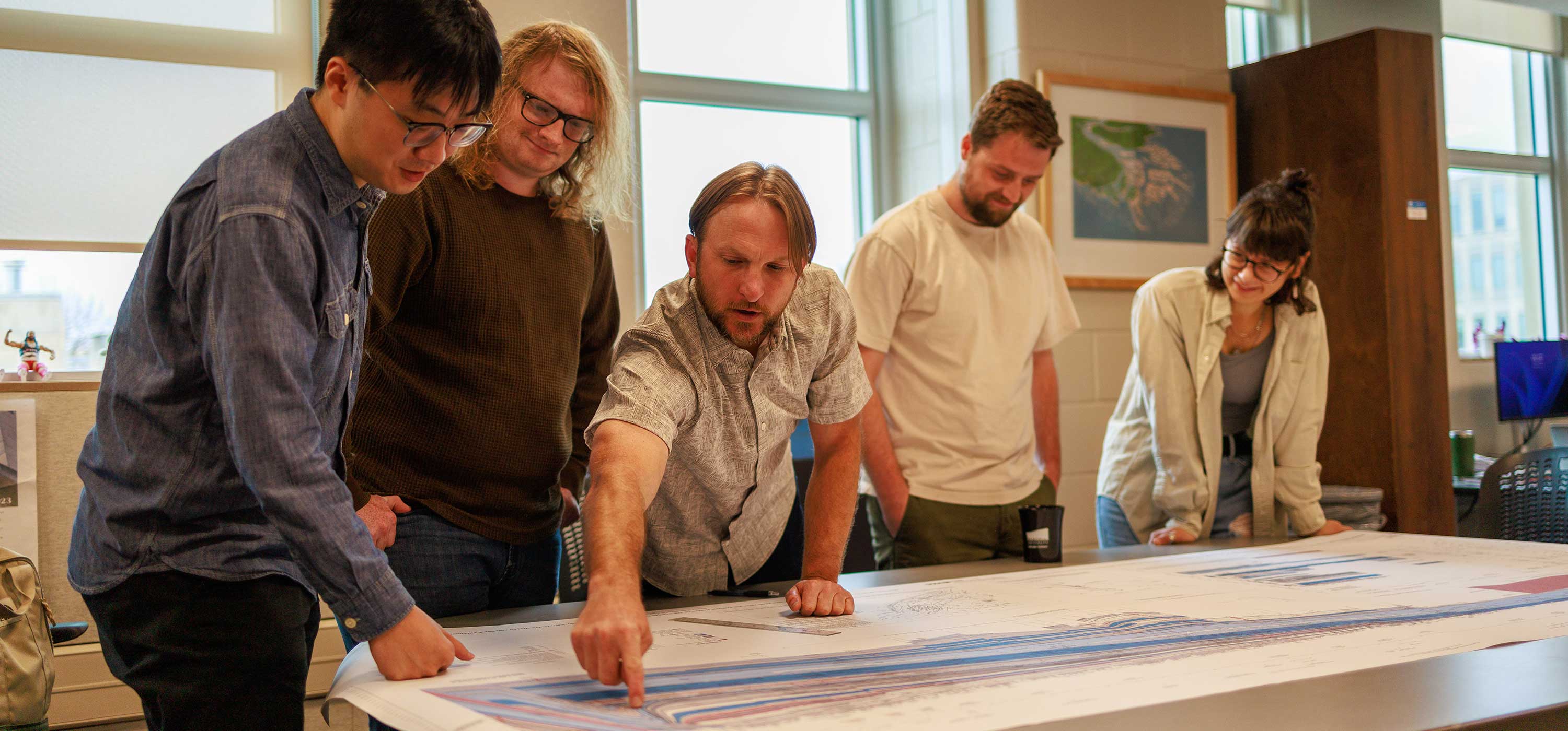 Professor Doug Edmonds points to a spot on a topographical map while four of his students look on.