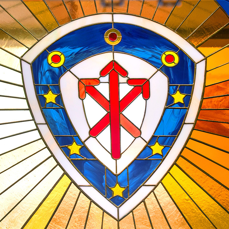 A photo of the College's heraldic banner on stained glass.